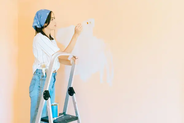 Interior painting in Manchester: painter on a stepladder rolling a wall